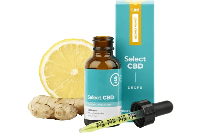 Select CBD Drops in lemon ginger: an amber dropper bottle and its teal box beside a slice of lemon and a piece of ginger root